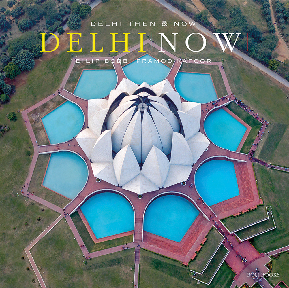 Aerial shot of Lotus Temple in India, New Delhi, DELHI THEN AND NOW DELHI NOW in white and yellow font above.