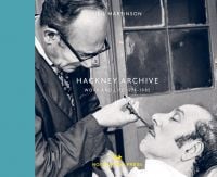 Book cover of Neil Martinson's Hackney Archive, Work and Life 1971-1985, with barber using pair of scissors to cut man's moustache as he sits back in chair. Published by Hoxton Mini Press.