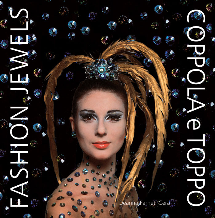 Fashion model with blue beaded hairpiece throwing out long golden feathers, on cover of 'Fashion Jewels, Coppola E Toppo', by ACC Art Books.