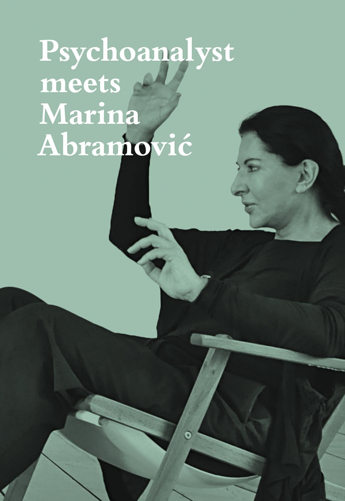 Marina Abramovic in black, seated, with hands in air, on mint green cover of 'Psychoanalyst Meets Marina Abramovic, Artist meets Jeannette Fischer', by Scheidegger & Spiess.