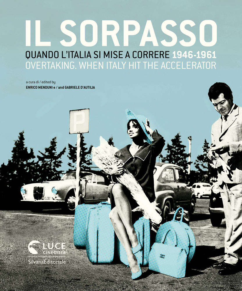 Woman sitting on luggage bags, holding flower bouquet, man standing to right, OVERTAKING. WHEN ITALY IT THE ACCELERATOR in white font above