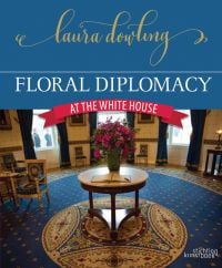 Book cover of Laura Dowling's Floral Diplomacy, At the White House, featuring the interior of the Blue Room, with large bouquet of pink flowers on table with open guest book. Published by Stichting.