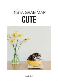 Kitten curled up in weigh scales bowl, on wood table, vase of daffodils to left, on cover of 'Insta Grammar: Cute', by Lannoo Publishers.