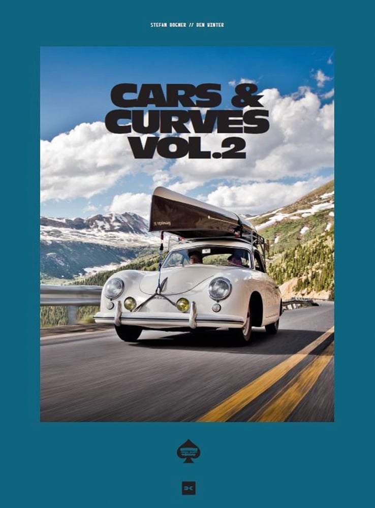 Cream Porsche 356 with small boat on roof rack travelling on road with mountains behind, on cover of 'Cars & Curves Vol.2', by Delius Klasing Verlag GmbH.