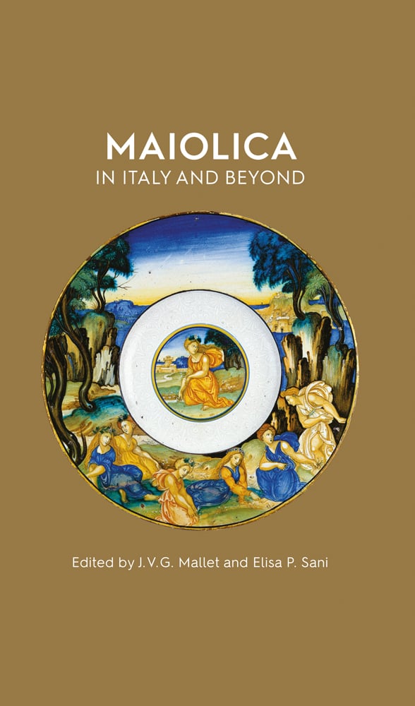 Maiolica dish with gold edge and landscape painting on gold brown cover of 'Maiolica in Italy and Beyond, Papers of a symposium held at Oxford in celebration of Timothy Wilson's Catalogue of Maiolica in the Ashmolean Museum', by Ashmolean Museum.