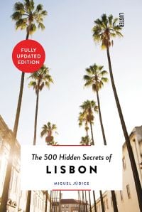 Row of towering palm trees down sunny street, on cover of 'The 500 Hidden Secrets of Lisbon', by Luster Publishing.