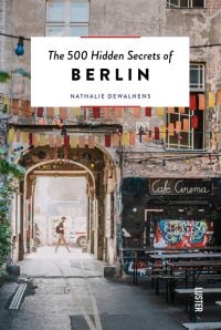 Café Cinema bench with bunting and street art in Berlin, on cover of 'The 500 Hidden Secrets of Berlin', by Luster Publishing.