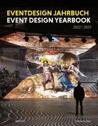 Exhibition space, man looking at figure with wings fighting figure with sword, on cover of 'Event Design Yearbook 2022 / 2023', by Avedition Gmbh.