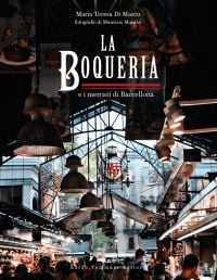 Barcelona's La Boqueria food market, large lights hanging from ceiling above crowds of shoppers and tourists, on cover of 'The Boqueria', by Guido Tommasi Editore.