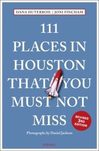 Space rocket near centre of blue cover of '111 Places in Houston That You Must Not Miss', by Emons Verlag.