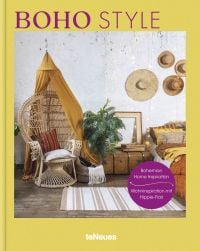 Large rattan chair draped with mustard coloured ceiling fabric, floppy hats on wall, on yellow cover of 'Boho Style, Bohemian Home Inspiration', by teNeues Books.
