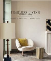 Fluffy cream covered chair with yellow cushion, floor lamp, on cover of 'Timeless Living Yearbook 2024', by Beta-Plus.