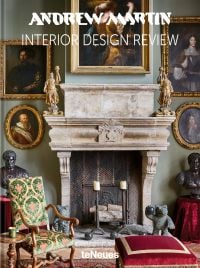 Interior living room of La Maison Semonville with stone fireplace, framed paintings and plush furniture, on cover of 'Andrew Martin Interior Design Review Vol. 27', by teNeues Books.