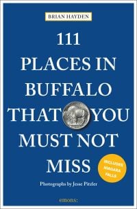Buffalo five cents coin near centre of dark blue travel guide cover of '111 Places in Buffalo That You Must Not Miss' by Emons Verlag.