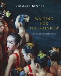 Book cover of Xiomara Bender's Waiting for the Rainbow: Ten Years in North Korea, with a group of dancers lining up in red costumes. Published by teNeues Books.