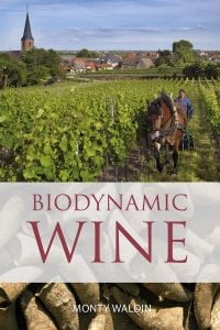 Book cover of Monty Waldin's Biodynamic wine, with a vineyard being ploughed by a horse, and a worker behind guiding plough. Published by Academie du Vin Library.