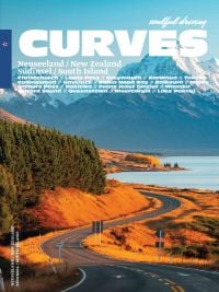 Book cover of Stefan Bogner's CURVES New Zealand: Volume 22, with a winding road on the coast, with snow covered mountains behind. Published by Delius Klasing.