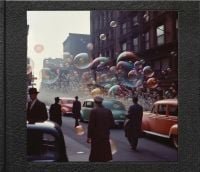 Book cover of Phillip Toledano's Another America, with figures in long coats walking up a New York street alongside 1940s cars with large colored bubbles floating in the air. Published by L'Artiere.