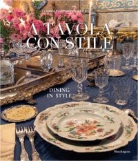 Book cover of Dining in Style: Between the Traditional and the Contemporary, featuring a classical dining table with crystal glasses and floral, porcelain plates. Published by Mandragora.