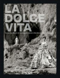 Book cover of La Dolce Vita: Inside the World of Dolce&Gabbana’s Alta Moda Fashion Shows, featuring a model in a large floral dress standing amongst a rocky mountain. Published by ACC Art Books.