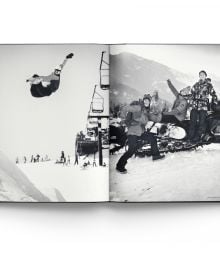 Female snowboarder sliding down rail of steps covered in snow, on cover of 'Heroes, Women in Snowboarding', by ACC Art Books.