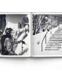 Female snowboarder sliding down rail of steps covered in snow, on cover of 'Heroes, Women in Snowboarding', by ACC Art Books.