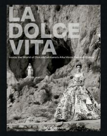 Book cover of La Dolce Vita: Inside the World of Dolce&Gabbana’s Alta Moda Fashion Shows, featuring a model in a large floral dress standing amongst a rocky mountain. Published by ACC Art Books.