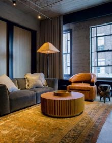 Book cover of Interiors Inside the American Home, feature a bright, open plan interior with pale furniture and large windows looking out onto cityscape, Published by Images Publishing.