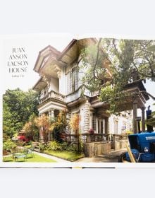 Grand interior with dark wood staircase, chandelier and stained glass interior windows, on cover of 'Houses that Sugar Built, An Intimate Portrait of Philippine Ancestral Homes', by ORO Editions.
