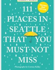 Book cover of Harriet Baskas' 111 Places in Seattle That You Must Not Miss, with a yellow umbrella surrounded by rain drops. Published by Emons Verlag.