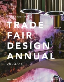 Book cover of Brand Experience & Trade Fair Design Annual 2023/24, with an interior of design exhibition with tropical foliage and metal tubes descending from above. Published by Avedition Gmbh.