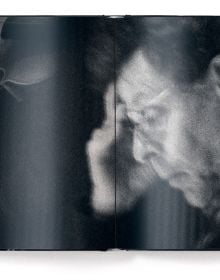 Book cover of dots on paper, Philip Glass by Andreas H. Bitesnich, with the composer in dark jacket, holding circular piece of glass to right eye. Published by teNeues Books.