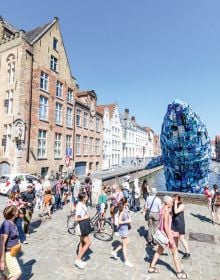 Book cover of 2018 Bruges Triennial: Liquid City, with a large red and yellow cocoon installation, floating on water with locks. Published by Stichting Kunstboek.