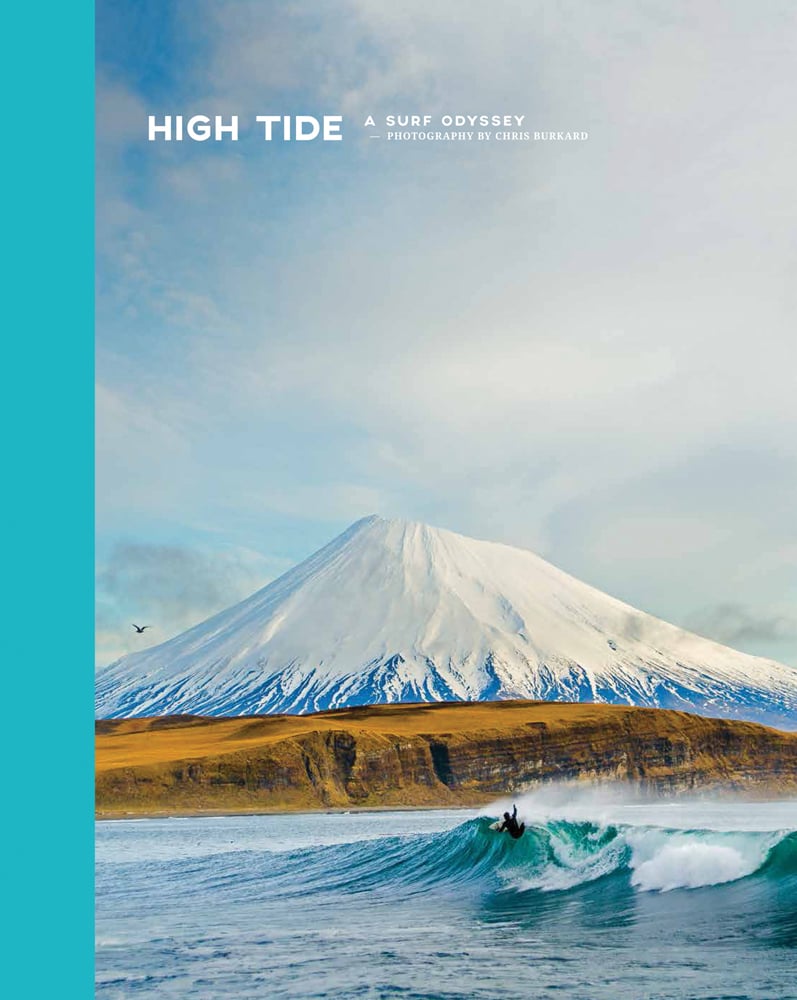 Book cover of Chris Burkard's High Tide, A Surf Odyssey, with cold-water surfer Josh Mulcoy surfing in front of Mount Vsevidof in the Aleutian Islands. Published by Lannoo Publishers.