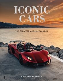 Book cover of Iconic Cars: The Greatest Modern Classics, with a dark red Lamborghini Aventador J Roadster parked on the coastline. Published by Lannoo Publishers.