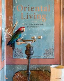 Book cover of Oriental Living, with a parrot on an ornate perch, with copper and blue walls. Published by Lannoo Publishers.