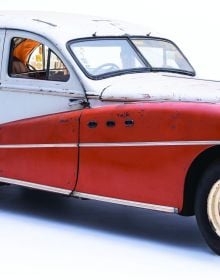 Old unrestored classic car with light blue panels on white cover of 'Mahy. A Family of Cars, The Tranquil Beauty of Unique Classic Cars', by Lannoo Publishers.