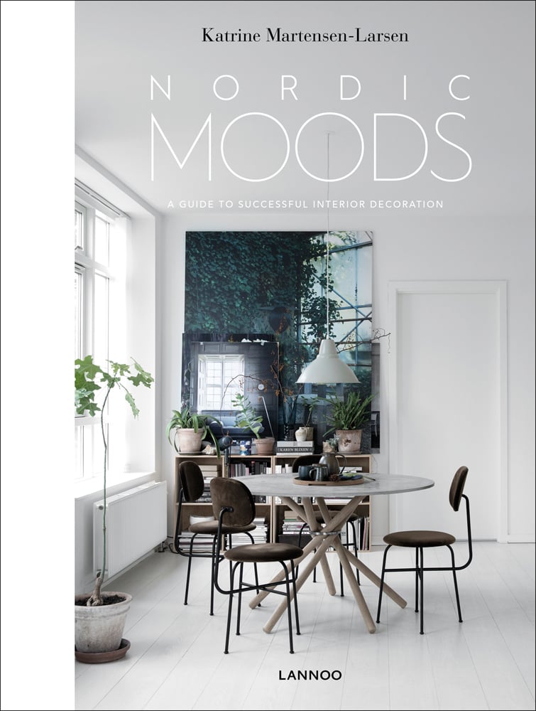 Book cover of Nordic Moods: A Guide to Successful Interior Decoration, featuring a minimalist dining interior, table and chairs, low light fixing, white walls. Published by Lannoo Publishers.