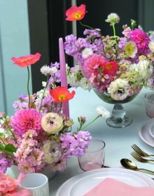 Wood table with vase of flowers, candlesticks, glasses and bowls, on cover of 'Table Stories, Tables for All Occasions', by Lannoo Publishers.