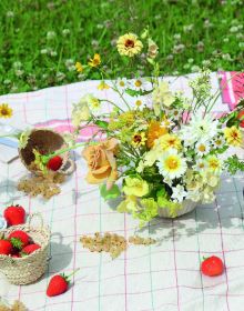 Wood table with vase of flowers, candlesticks, glasses and bowls, on cover of 'Table Stories, Tables for All Occasions', by Lannoo Publishers.