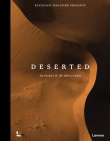 Book cover of Deserted: In Pursuit of Drylands, with an aerial view of desert landscape with sand dunes. Published by Lannoo Publishers.