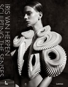 Book cover of Iris van Herpen, Sculpting the Senses, with model wearing white sculptural snake-like shoulder piece. Published by Lannoo Publishers.