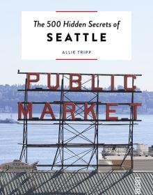 Book cover of The 500 Hidden Secrets of Seattle with the Pike Place market unlit neon sign above corrugated roof. Published by Luster Publishing.