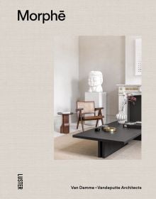 Linen book cover of Morph?, Van Damme - Vandeputte Architects, with an Interior space with low black coffee-table, white bust sculpture on plinth, wood chair, and white marble fireplace. Published by Luster Publishing.