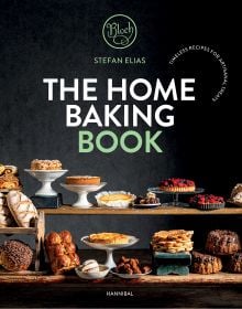 Book cover of The Home Baking Book: Timeless Recipes for Artisanal Treats, with a table of bread, pastries, cakes and tarts. Published by Hannibal Publishers.